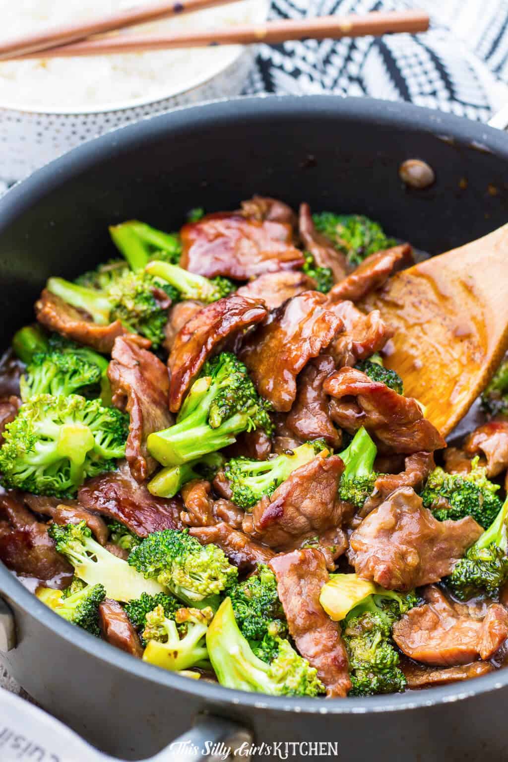 Beef and Broccoli in cooking pan with wooden spoon