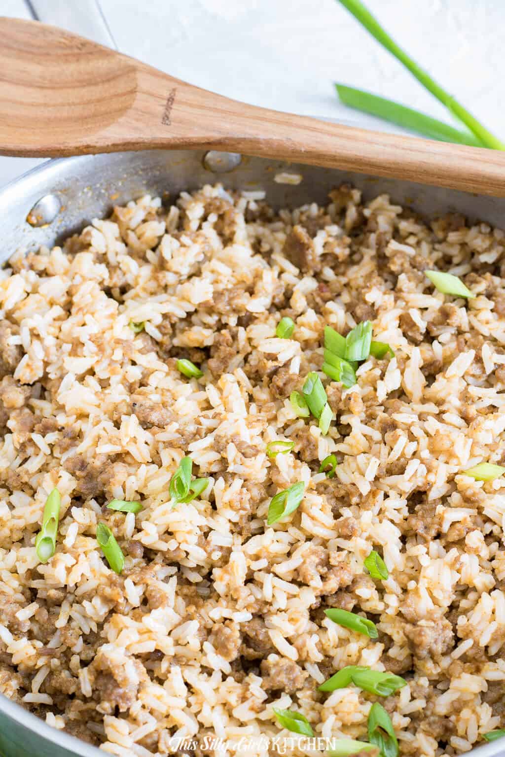 Sausage Dirty Rice close up in pan with wooden spoon.