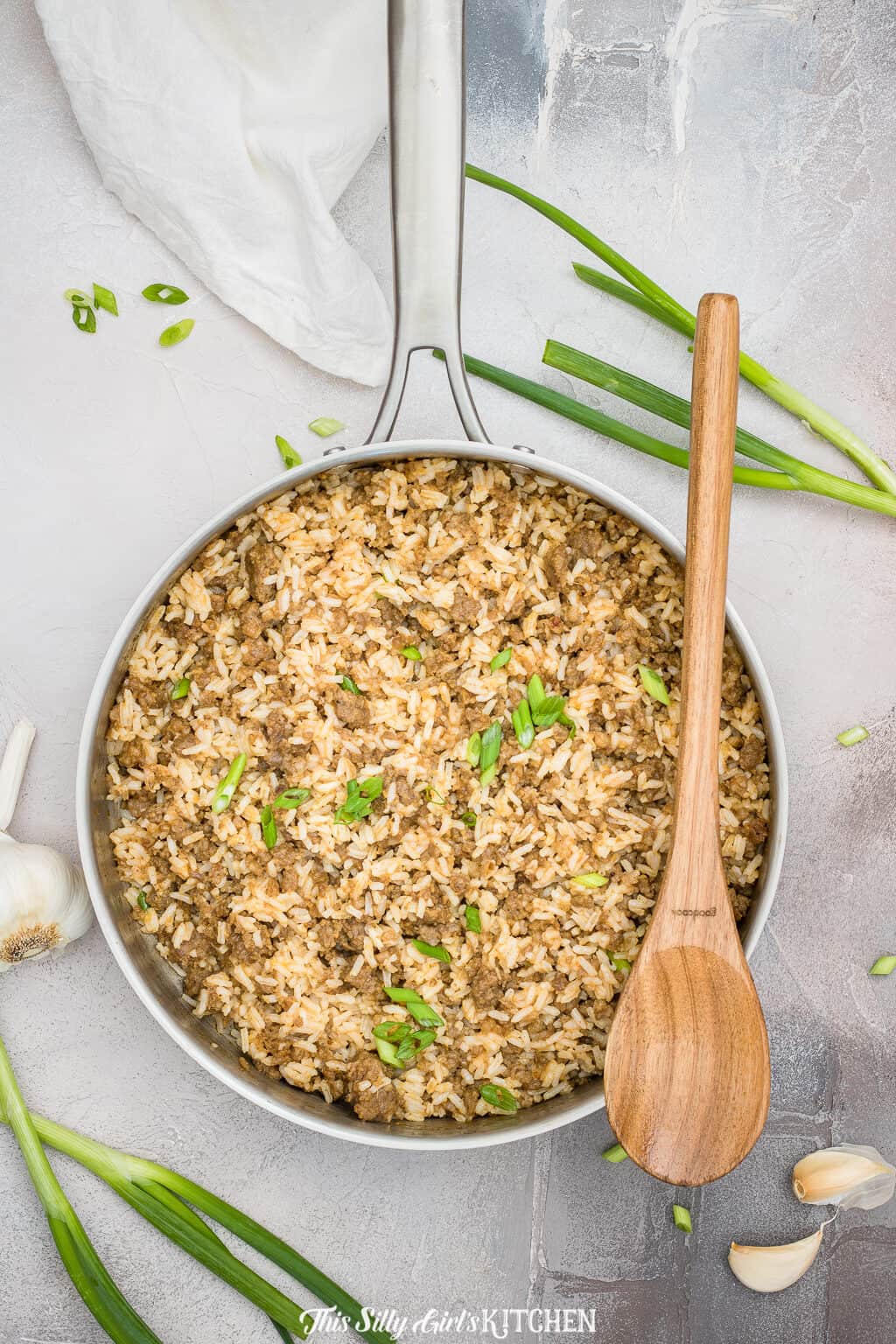 Dirty Rice in pan overhead with wooden spoon on pan.