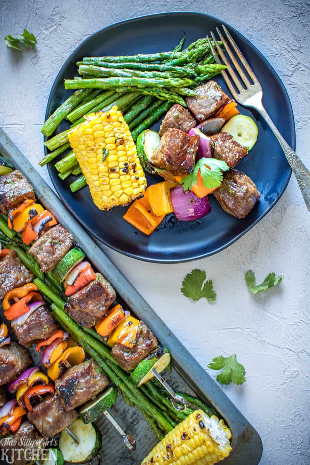 Overhead image of plated Kabobs with corn and asparagus.