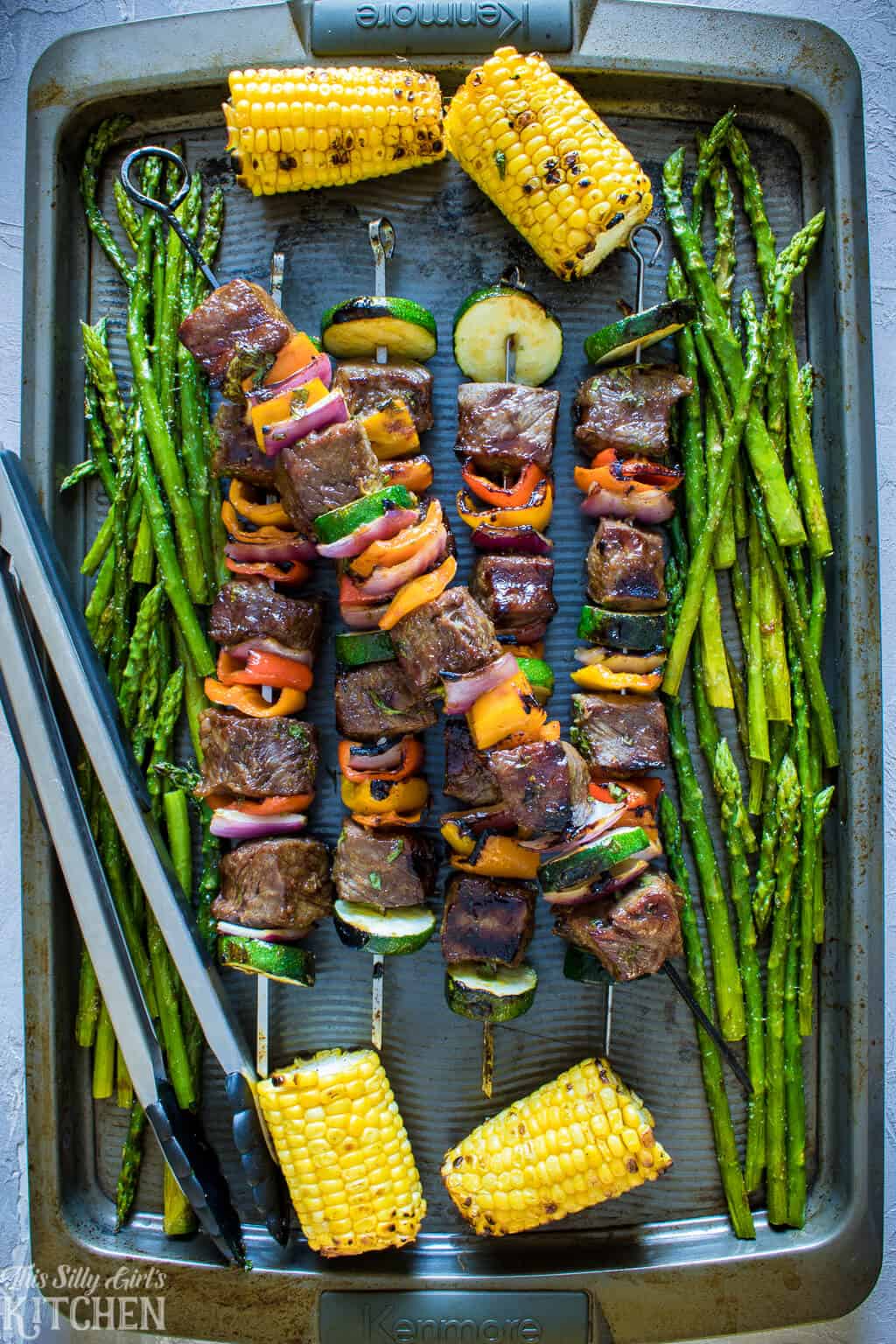 Carne Asada Steak Kabobs with corn and asparagus on baking pan.