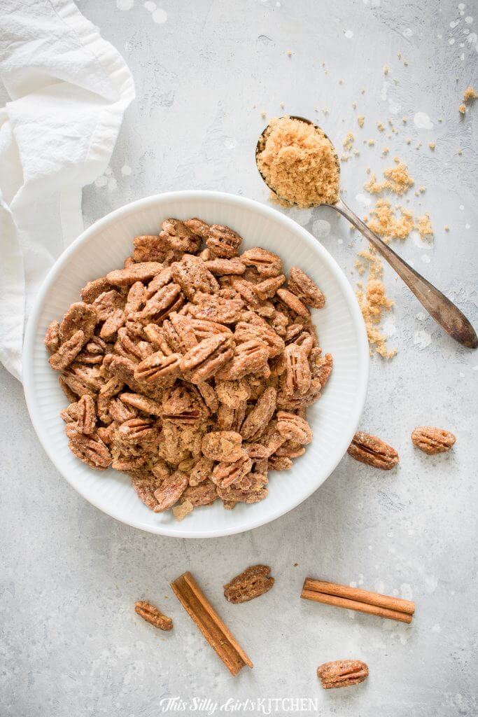 Overhead of Roasted Pecans in bowl with cinnamon and spoon of brown sugar