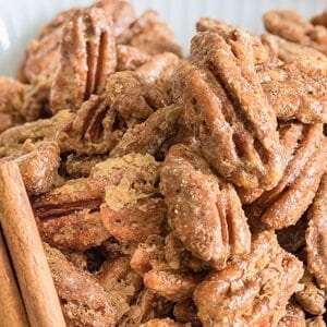 Candied pecans coated in cinnamon sugar piled in a white bowl.