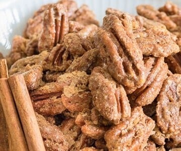 Roasted Pecans in white bowl close up with cinnamon sticks