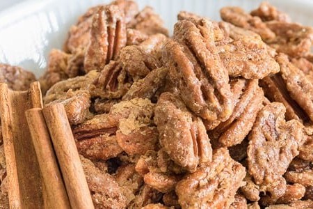 Roasted Pecans in white bowl close up with cinnamon sticks