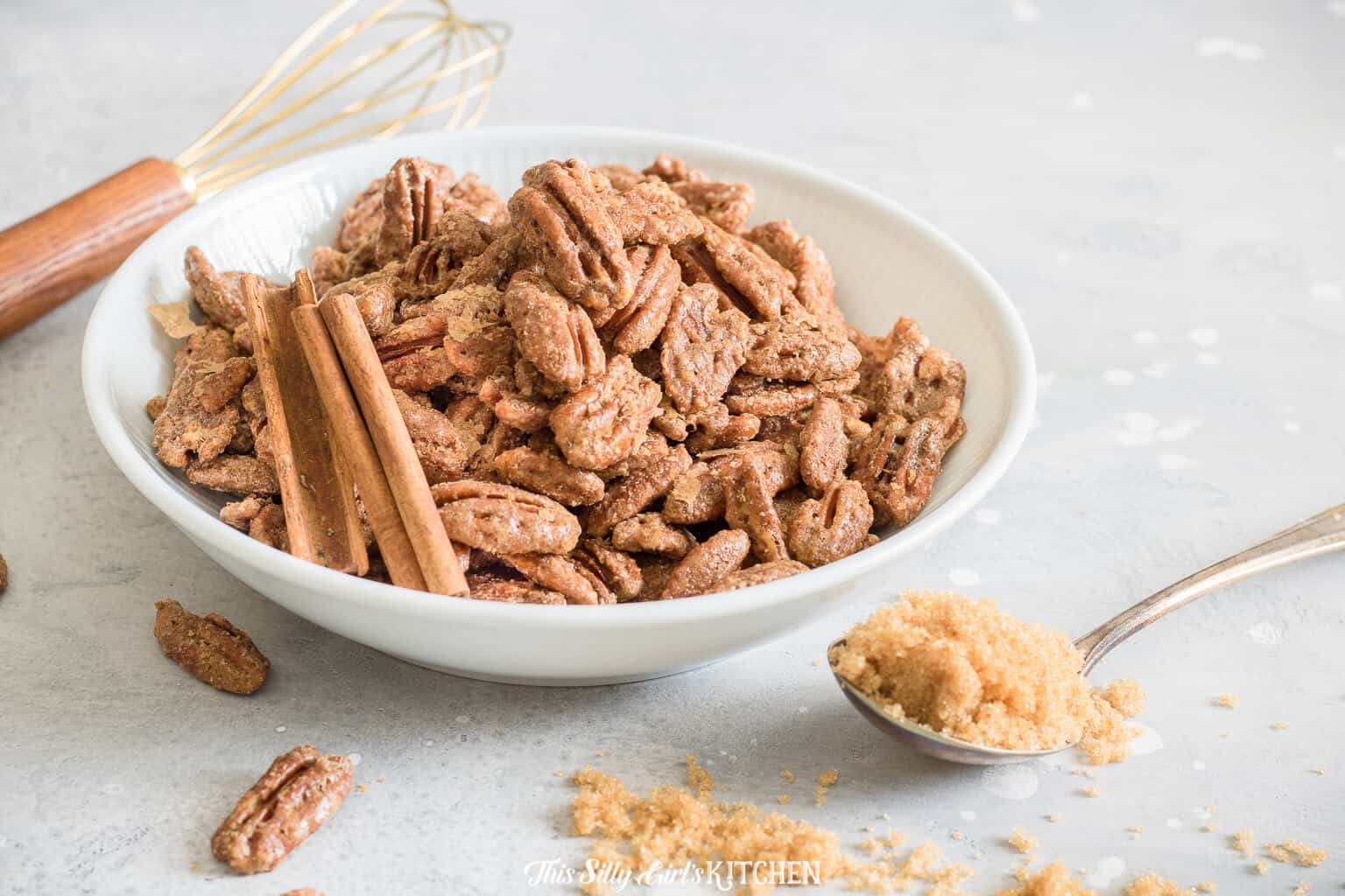 Horizontal photo of pecan sin white bowl with whisk and spoon of brown sugar