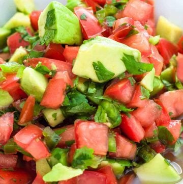 A white bowl of fresh avocado salsa with diced tomatoes, avocado, and cilantro.