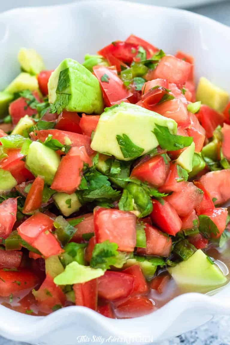 A white bowl of fresh avocado salsa with diced tomatoes, avocado, and cilantro.