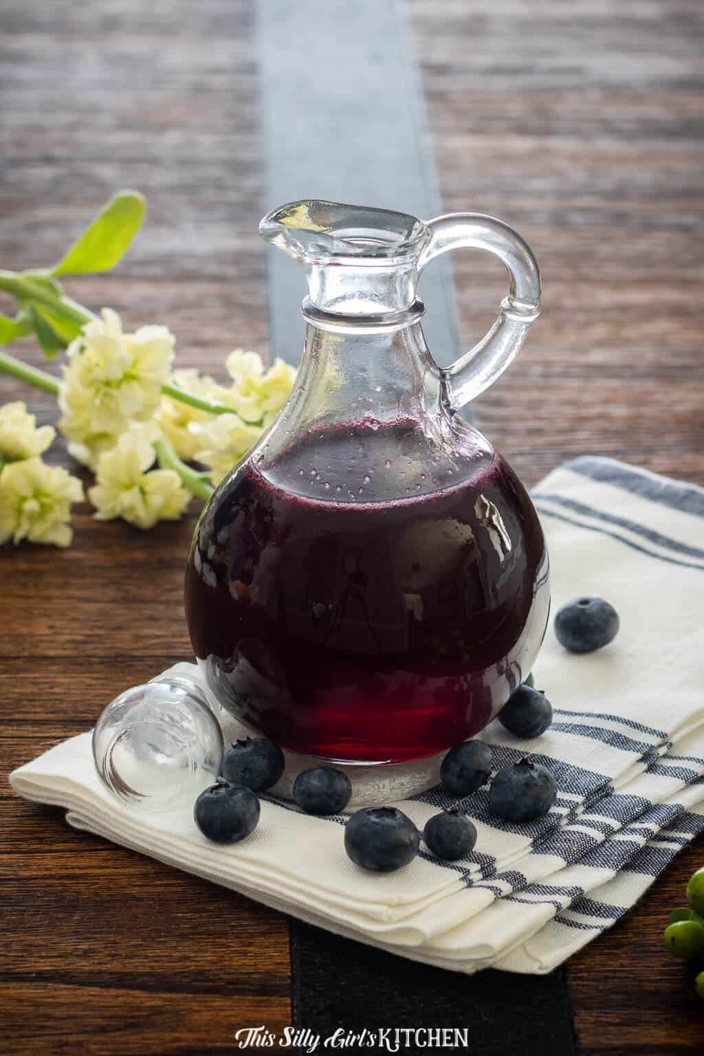 blueberry syrup in a glass container on a kitchen towel