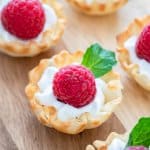 Raspberry Dessert Cups with lemon whipped cream, a fresh raspberry, and mint in a phyllo cup.