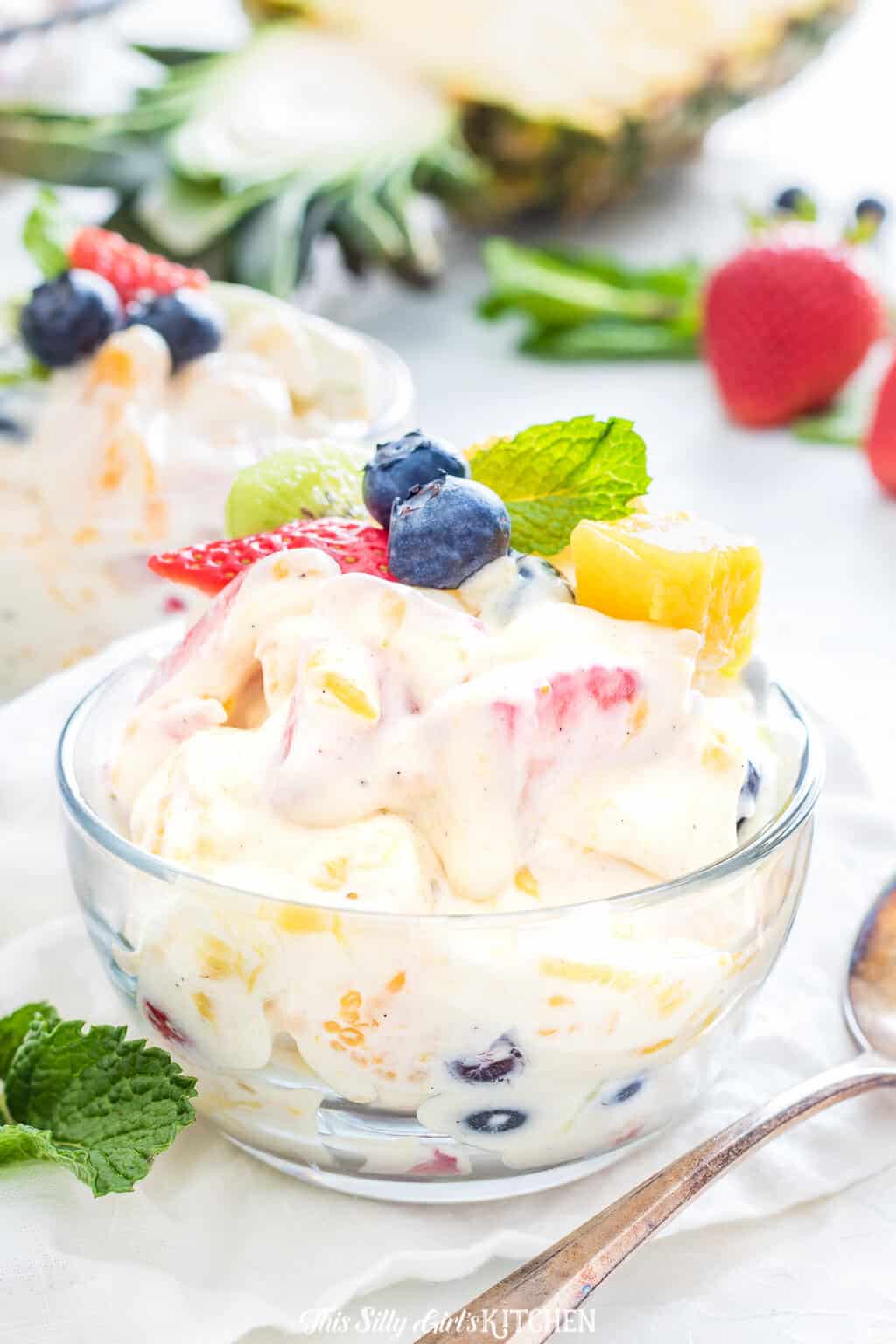 Cheesecake Salad in clear bowl topped with fruit and mint