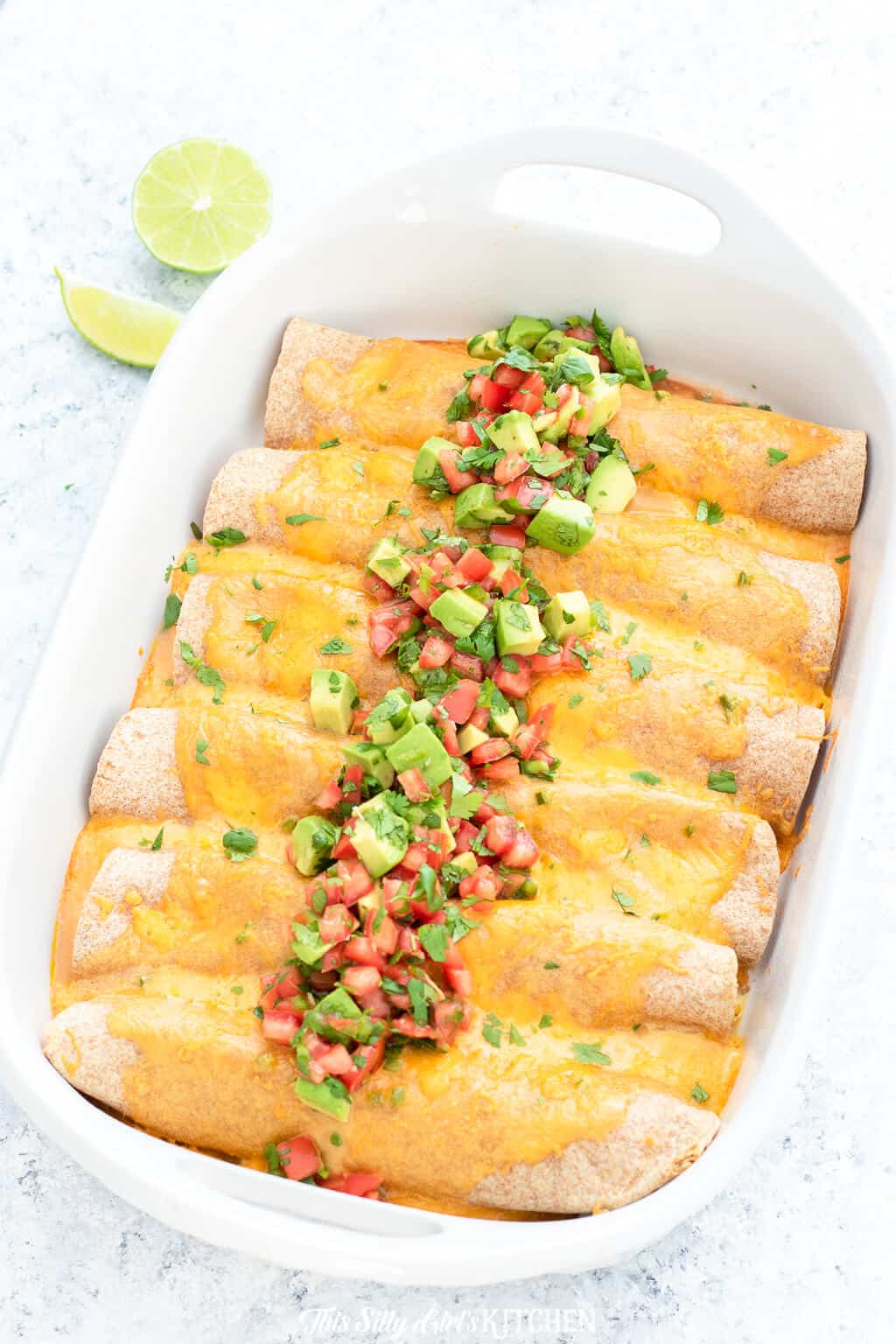 Overhead of Breakfast Enchiladas in baking dish topped with Avocado Salsa