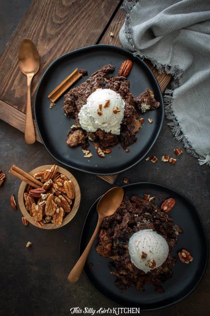 Overhead of cobbler on black plates topped with ice cream and pecans