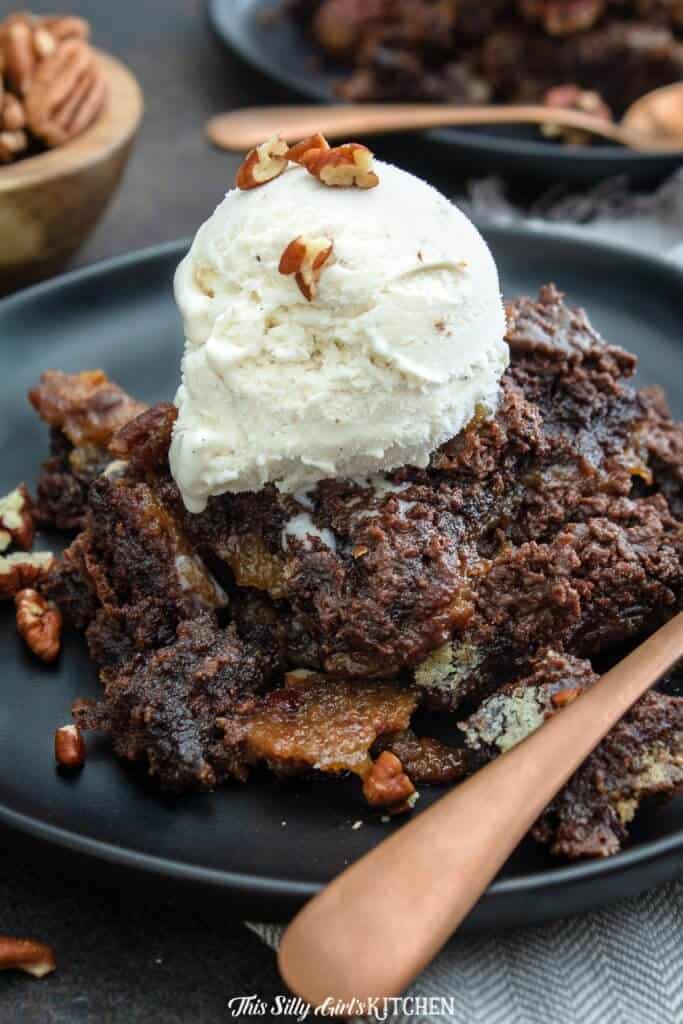 Chocolate Pecan Cobbler on black plate topped with ice cream 