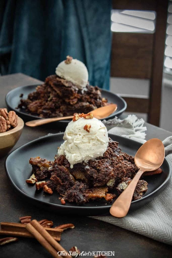 Two plates on table of cobbler with spoons topped with ice cream