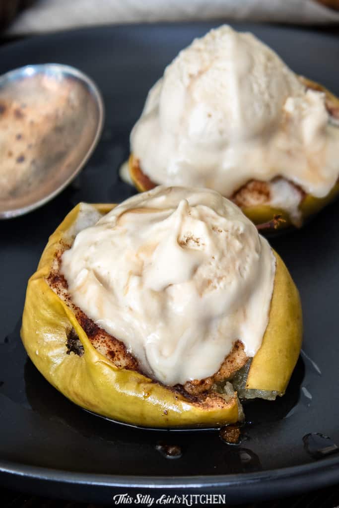 Two Baked Apples Recipe on plate with melting ice cream and spoon.