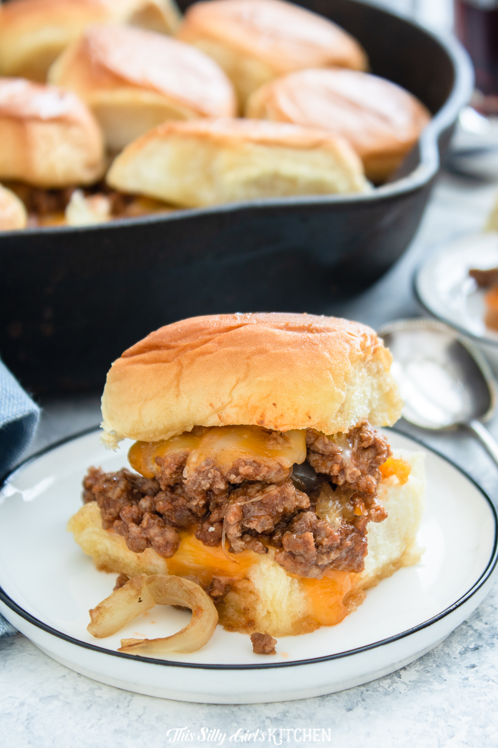 Sloppy Joe Sliders: Sloppy joe mix on top of slider buns with melty cheese and caramelized onions, baked until bubbly. #recipe from thissillygirlskitchen.com #sloppyjoe #sliders #gamedayfood 