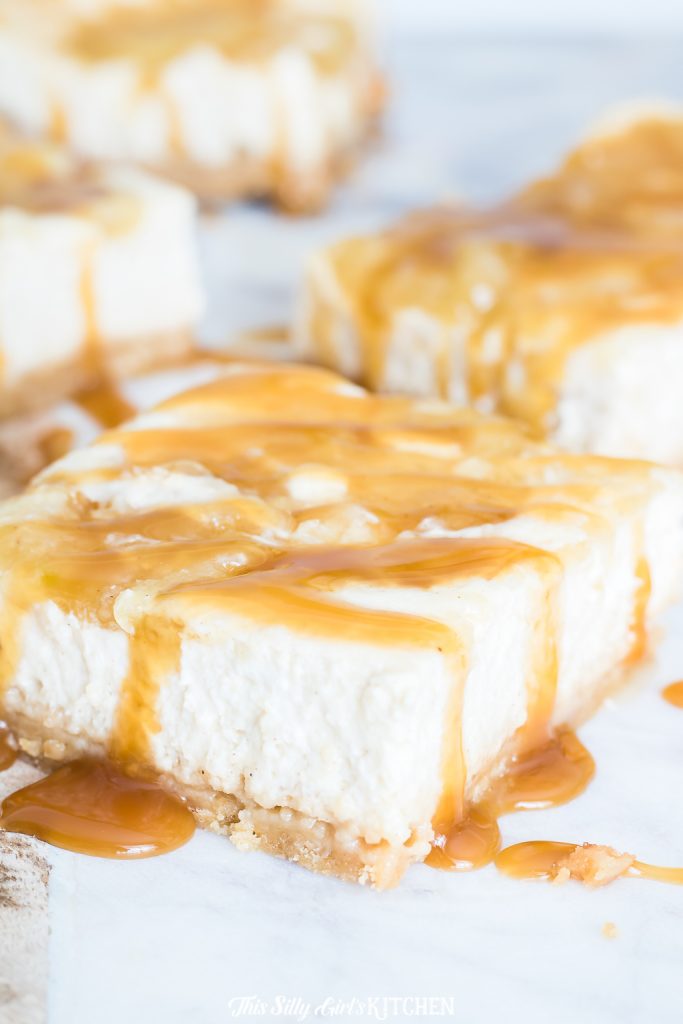Close up of cut cheesecake bar drizzled with caramel sauce