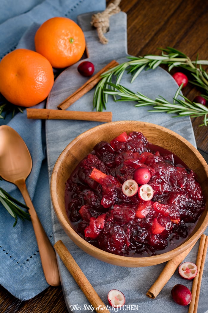 Bowl of Apple Cranberry Sauce with blue linen and herbs