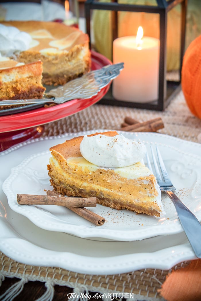 Slice of Pumpkin Cheesecake on white plate with fork and cinnamon sticks