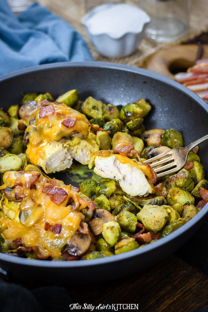 This alice springs chicken in skillet over Brussel sprouts with one breast cut with fork