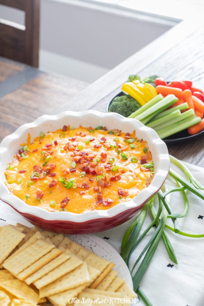 Bacon Ranch Chicken Dip in pie plate surrounded by crackers and vegetables