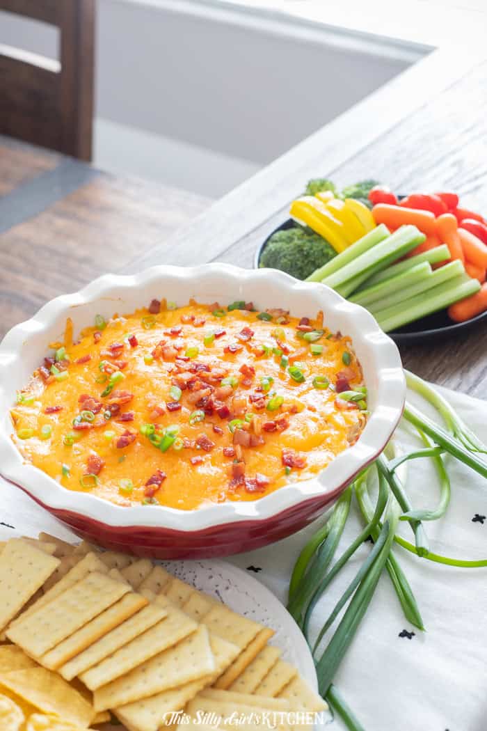 Cheesy bacon ranch crack chicken dip in a red baking dish.