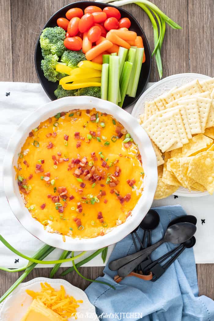 Crack chicken dip served with crackers and fresh vegetables.