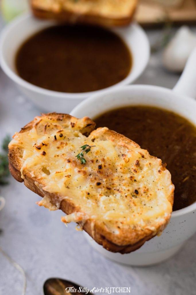 Close up of cheese coated bread on soup cup