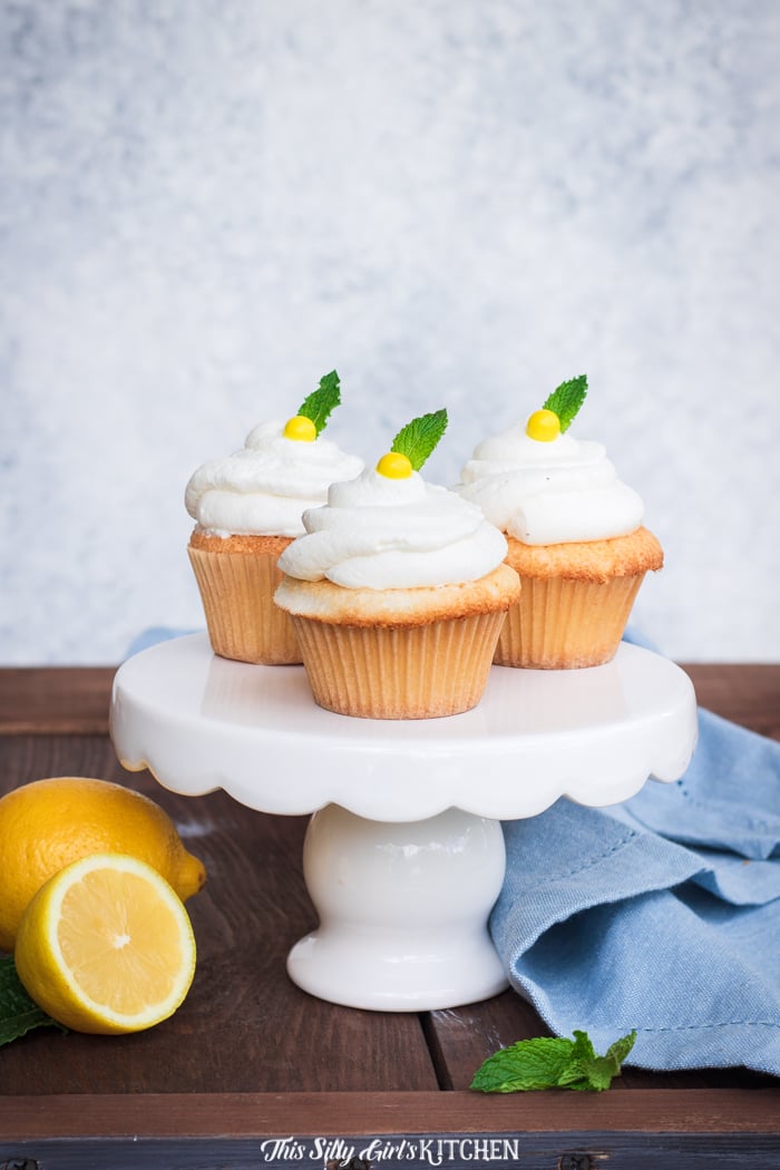 Three Lemon Cupcakes on small cake stand with mint and lemons