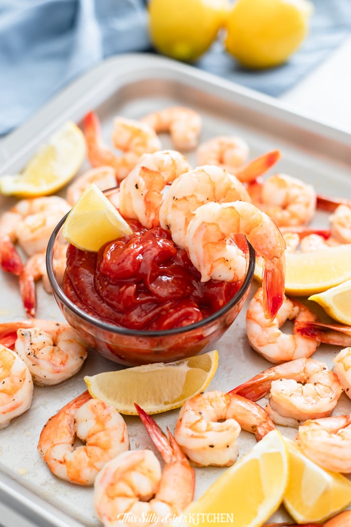 Roasted Shrimp Cocktail on sheet pan with cocktail sauce in middle 