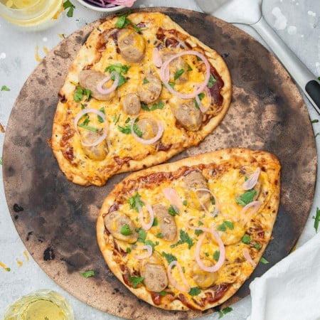 Square image of two BBQ Chicken Pizzas on pizza stone