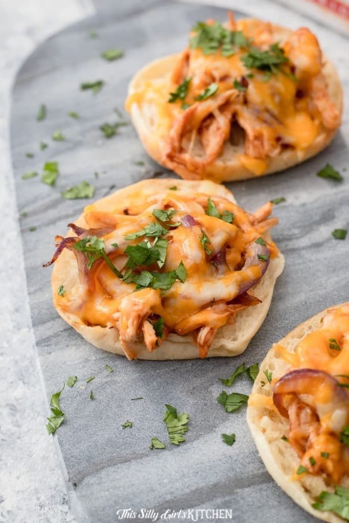 Mini BBQ Chicken Pizzas - English muffins topped with shredded bbq chicken, Colby jack cheese, red onions, and cilantro - YUM! #recipe from thissillygirlskitchen.com #pizza #minipizza #englishmuffinpizza #bbqchicken #bbqchickenpizza