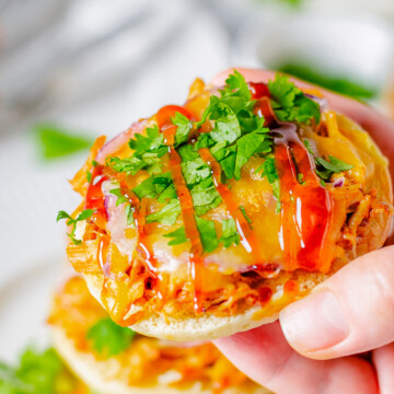handheld shot of english muffin pizza with bbq sauce