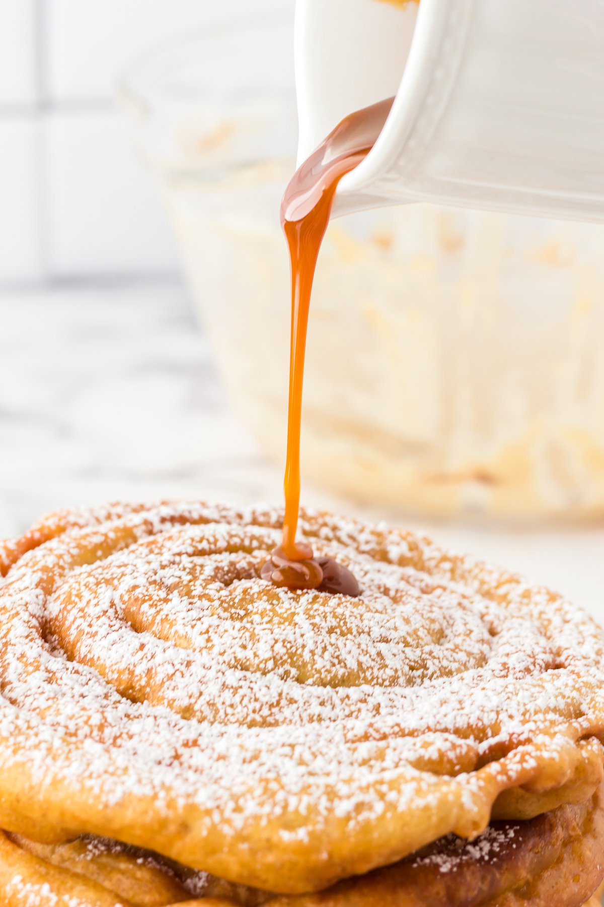 Caramel sauce being poured over Funnel Cakes