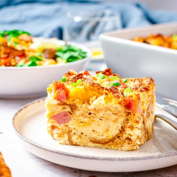 Close up side view of slice of Ham and Cheese Savory Bread Pudding showing layers on white plate.