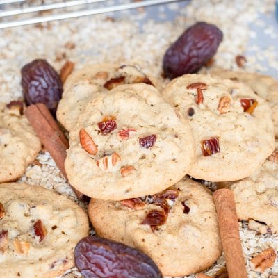 Soft oatmeal date cookies studded with chopped dates and pecans stacked on a plate.