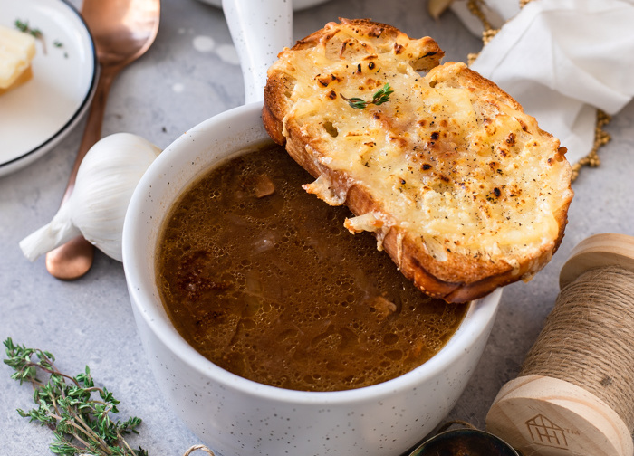 Horizontal image of soup with piece of bread on top.