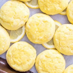 A close-up of soft meltaway lemon cookies rolled in sugar with fresh lemon slices.