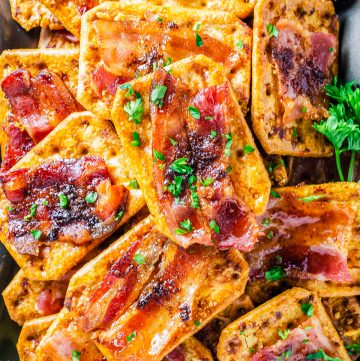 A platter of glazed Bacon Crackers topped with caramelized brown sugar bacon and fresh parsley.
