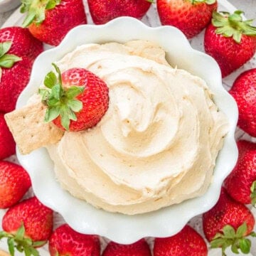A bowl of creamy fluffernutter dip surrounded by fresh strawberries, graham crackers, and vanilla wafers for dipping.