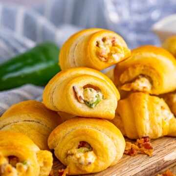 Stacked Jalapeño Popper Crescent Rolls on wooden board.