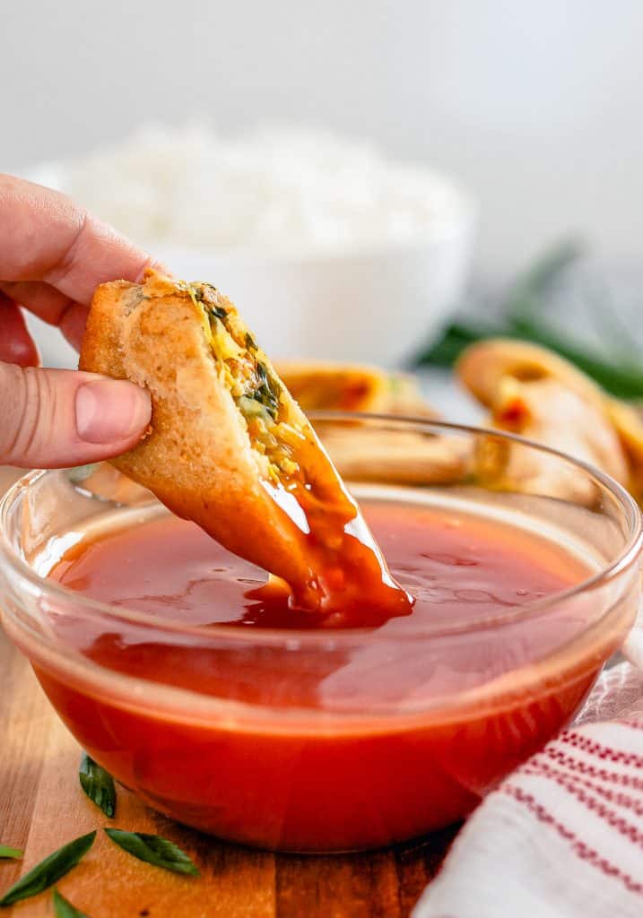 Egg roll being dipped into bowl of The Best Sweet and Sour Sauce.