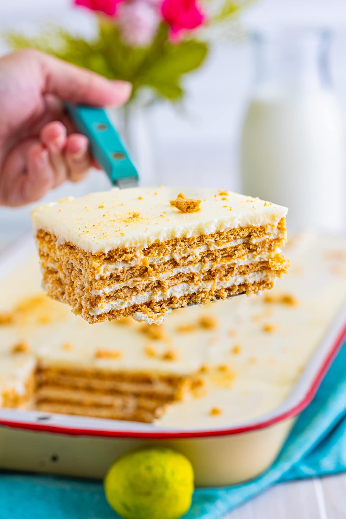 a hand holding a spatula with a piece of Eclair Cake in air