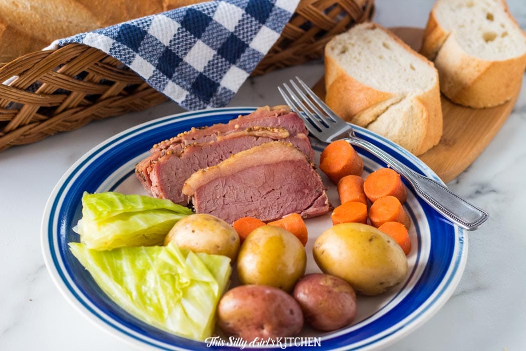 Plated Slow Cooker Corned Beef Dinner on white and blue plate with fork