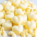 A pile of heart shaped white chocolate truffles with white chocolate chips.