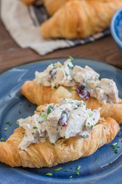 A croissant sandwich filled with creamy cranberry chicken salad on a blue plate.