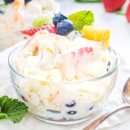 Square image of Tropical Cheesecake Salad in bowl topped with fruit
