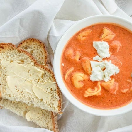 The best tomato soup in bowl with bread next to it square image