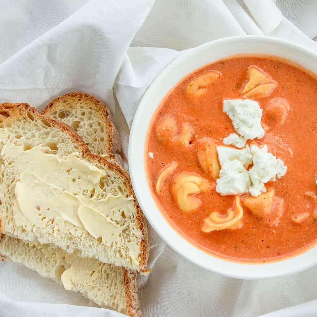 A bowl of creamy tomato soup loaded with cheese tortellini.